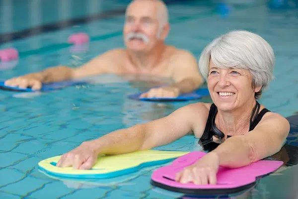 Deux seniors pratiquent l'aquagym avec des planches